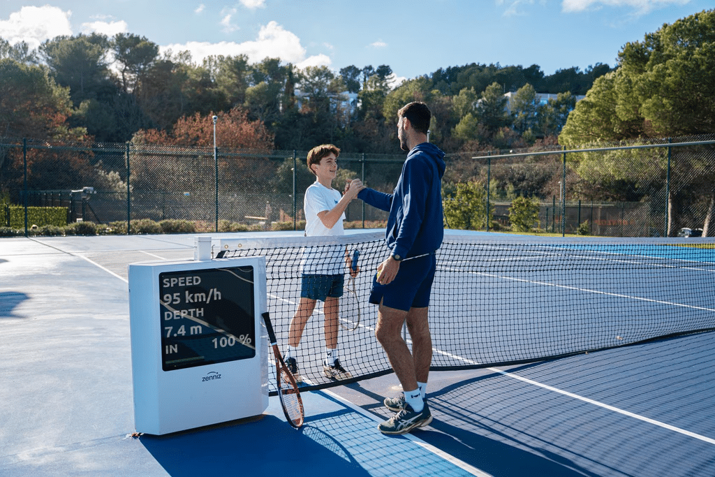 Træner og ung spiller med Zenniz-system ved tennisnettet